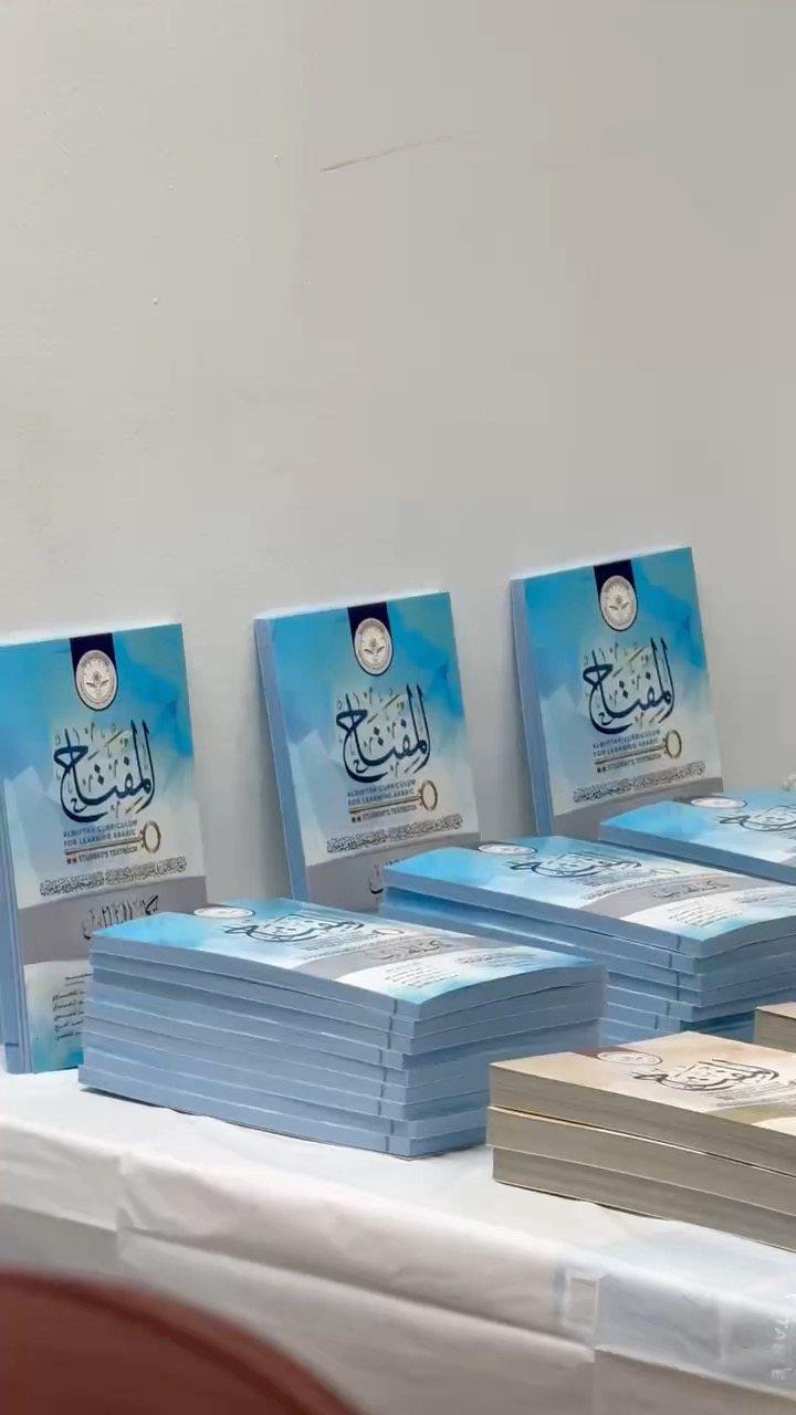 Stacks of blue al-Miftah Arabic textbooks on a table
