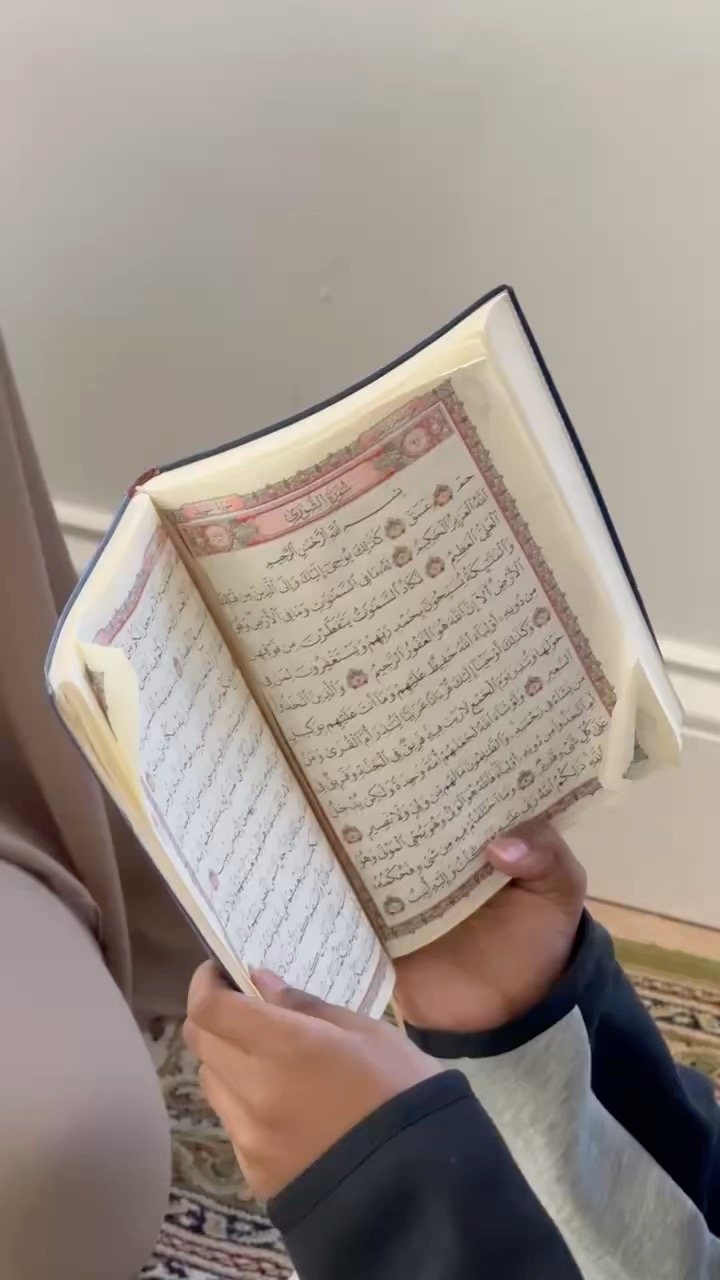 Close-up of hands holding an open mushaf