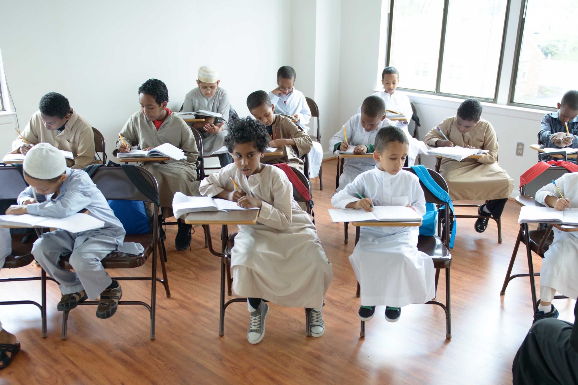 A classroom of boys memorizing at individual desks by the windows